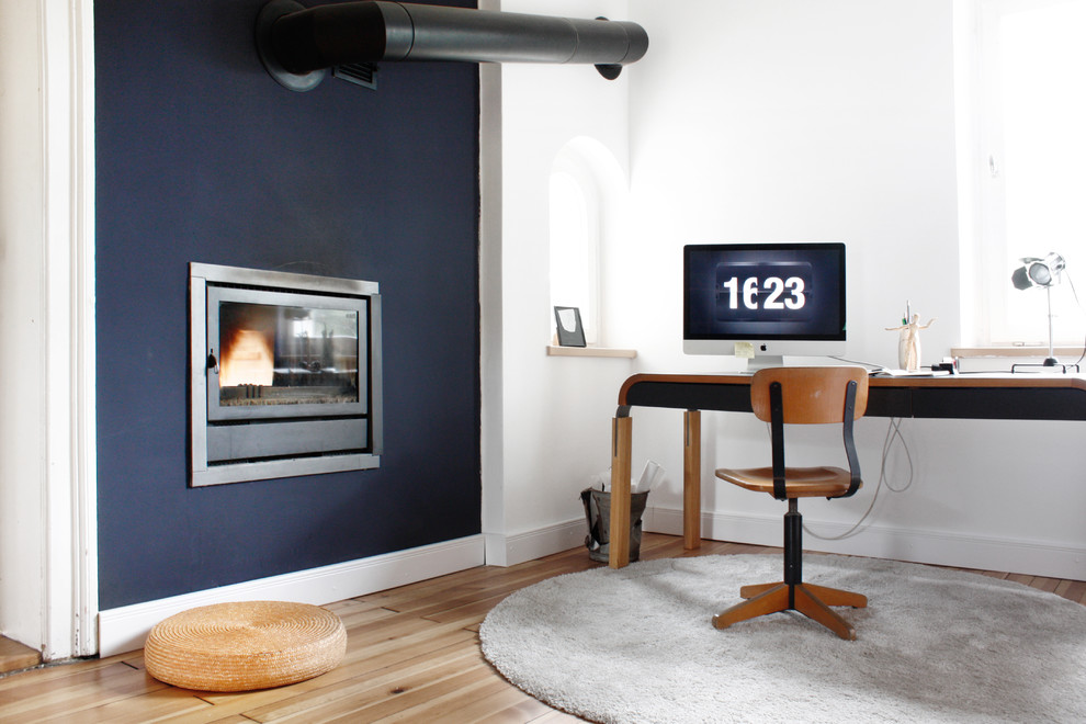 Cette photo montre un grand bureau scandinave avec un mur bleu, un sol en bois brun, une cheminée standard, un bureau indépendant et un manteau de cheminée en métal.