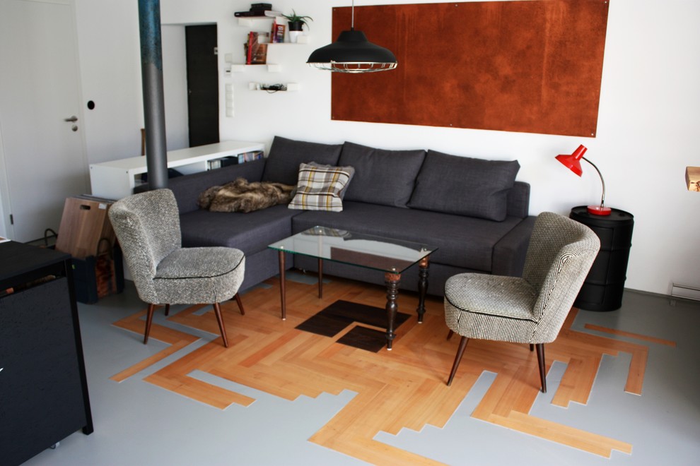 Imagen de estudio urbano pequeño con paredes blancas, suelo de madera en tonos medios y escritorio independiente