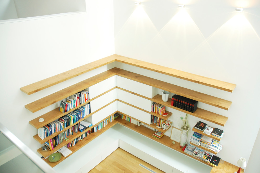 Geräumiges Modernes Lesezimmer ohne Kamin mit weißer Wandfarbe, braunem Holzboden, freistehendem Schreibtisch und braunem Boden in Frankfurt am Main