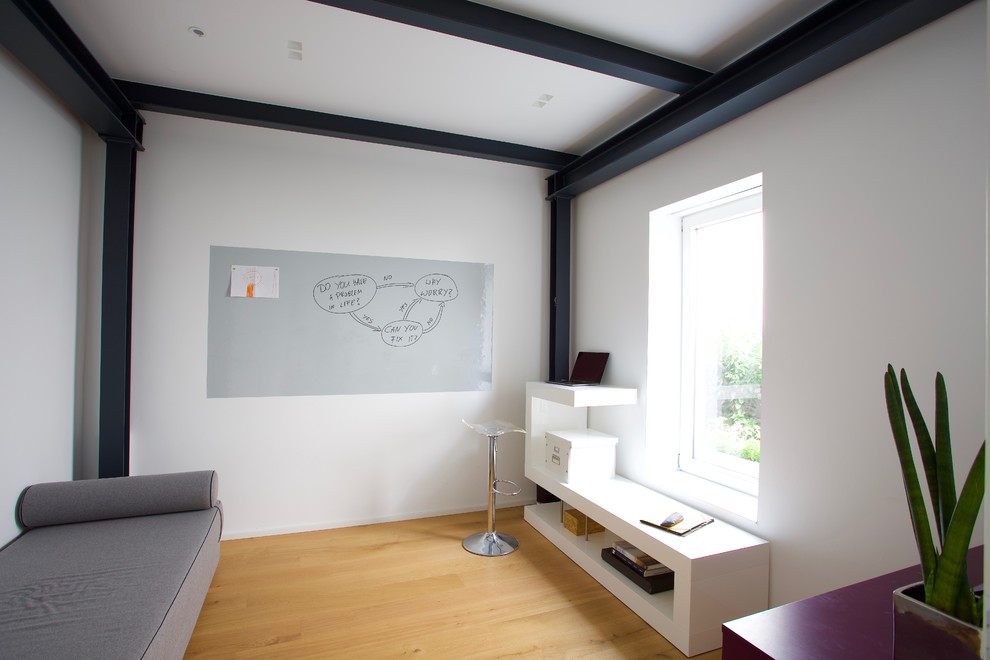Diseño de despacho moderno pequeño con paredes blancas, suelo de madera clara, escritorio independiente y suelo amarillo