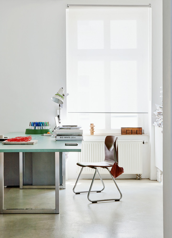 Großes Nordisches Arbeitszimmer ohne Kamin mit weißer Wandfarbe, Betonboden, freistehendem Schreibtisch und Arbeitsplatz in Hamburg