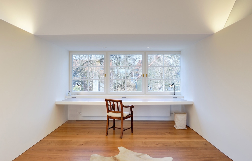 Imagen de despacho contemporáneo de tamaño medio sin chimenea con paredes blancas, suelo de madera en tonos medios y escritorio empotrado