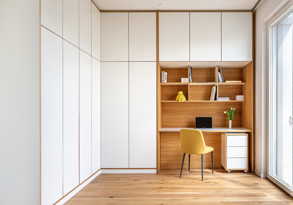 Modernes Arbeitszimmer mit Arbeitsplatz, hellem Holzboden, Einbau-Schreibtisch, weißer Wandfarbe und beigem Boden in Berlin