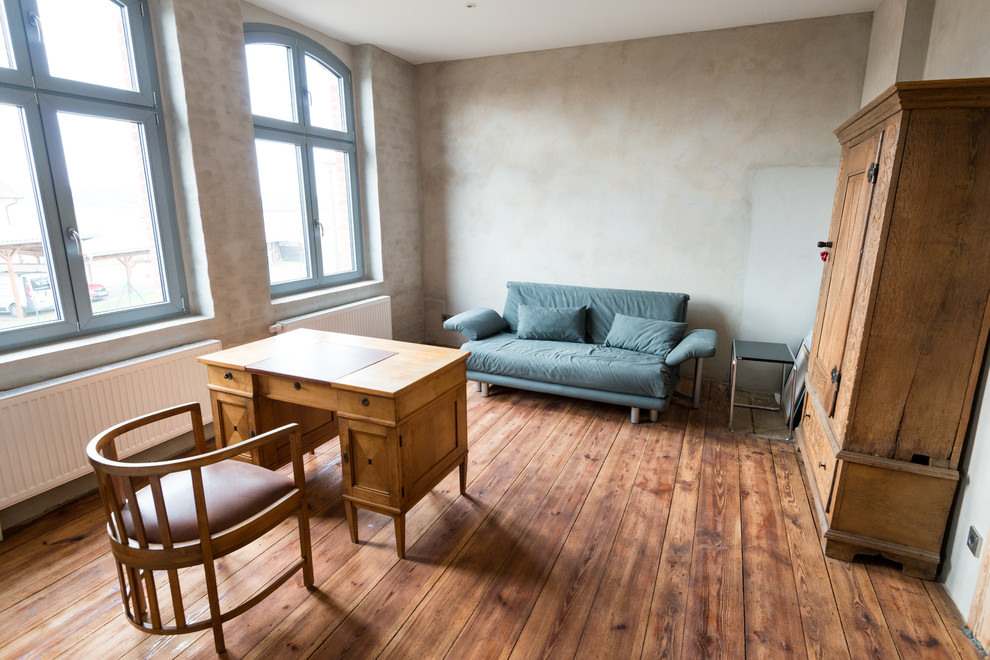 Mittelgroßes Klassisches Arbeitszimmer ohne Kamin mit Arbeitsplatz, beiger Wandfarbe, braunem Holzboden, freistehendem Schreibtisch und braunem Boden in Berlin