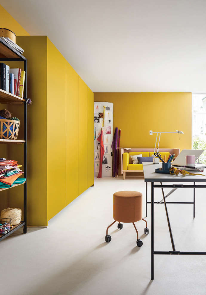 Modern inredning av ett stort hobbyrum, med gula väggar och vitt golv