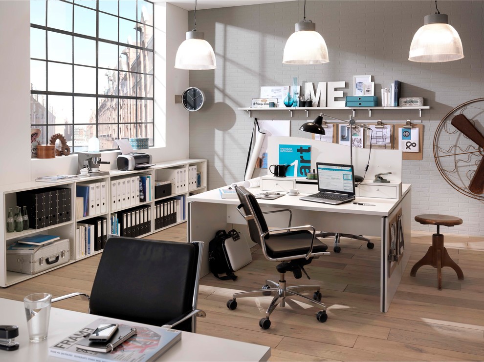 Mittelgroßes Industrial Arbeitszimmer ohne Kamin mit Arbeitsplatz, weißer Wandfarbe, Laminat, freistehendem Schreibtisch und braunem Boden in Dresden