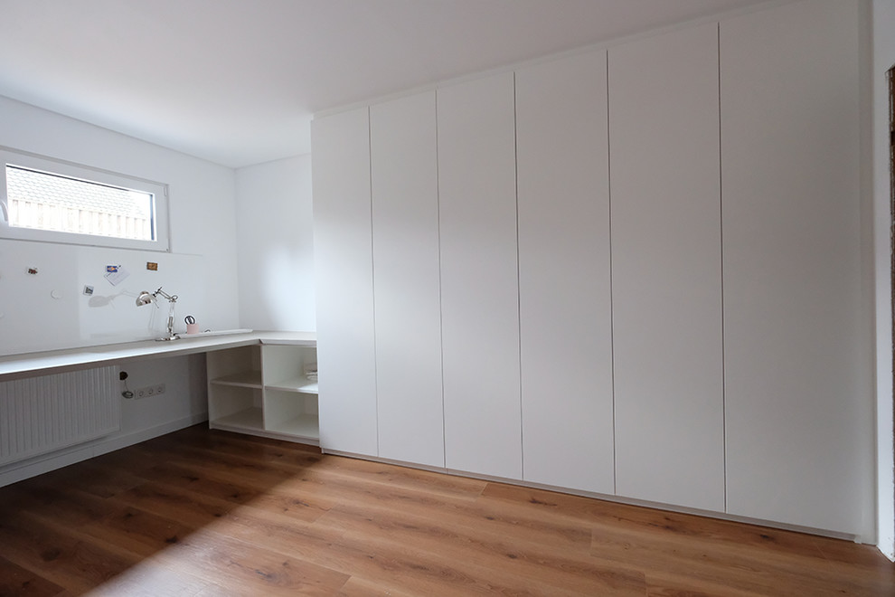 Großes Modernes Arbeitszimmer mit Arbeitsplatz, Einbau-Schreibtisch, weißer Wandfarbe, braunem Holzboden und braunem Boden in Sonstige