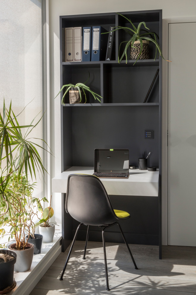 Immagine di un piccolo ufficio minimal con pareti bianche, scrivania incassata, pavimento in legno verniciato e pavimento grigio