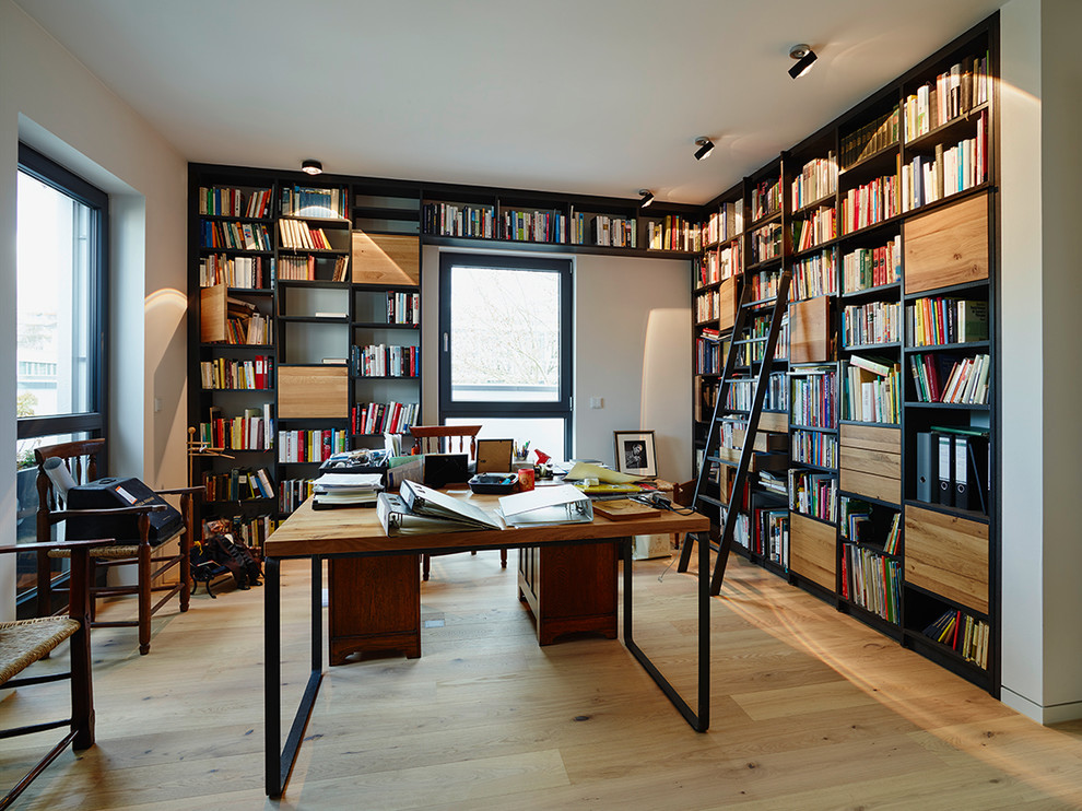 フランクフルトにある広いコンテンポラリースタイルのおしゃれなホームオフィス・書斎 (白い壁、淡色無垢フローリング、自立型机、暖炉なし、ライブラリー) の写真