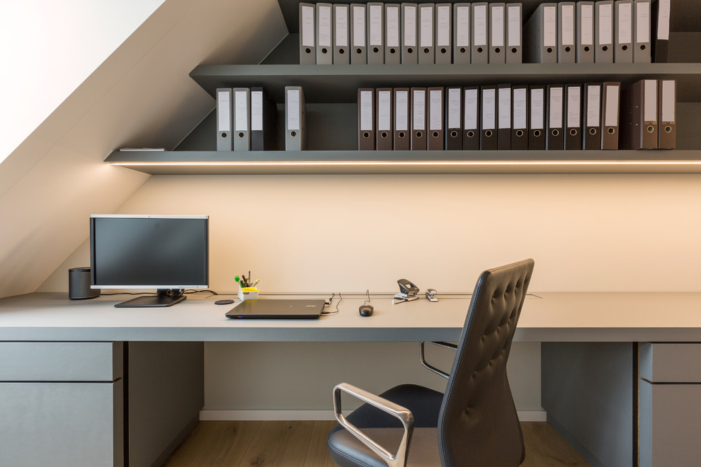 Esempio di un grande ufficio minimal con pareti beige, pavimento in legno verniciato, nessun camino, scrivania incassata e pavimento marrone