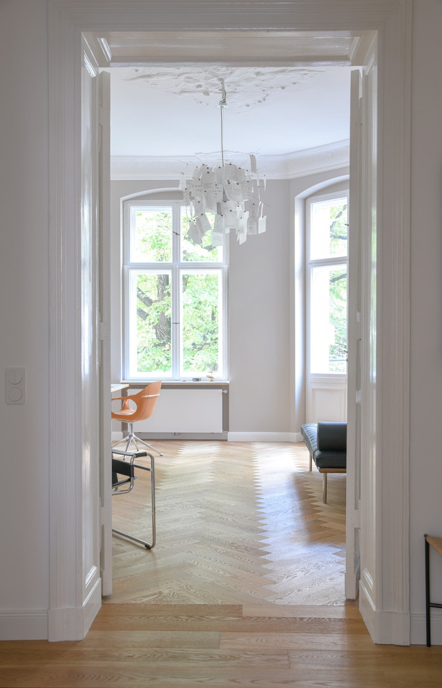 Diseño de estudio contemporáneo grande sin chimenea con paredes grises, suelo de madera clara y escritorio independiente