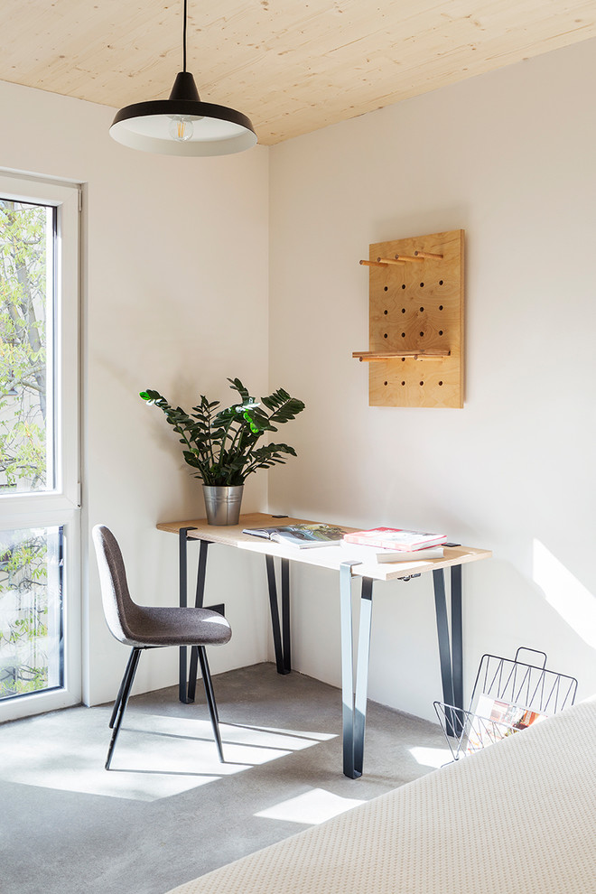 This is an example of a medium sized industrial home office in Berlin with white walls, concrete flooring, a freestanding desk and grey floors.