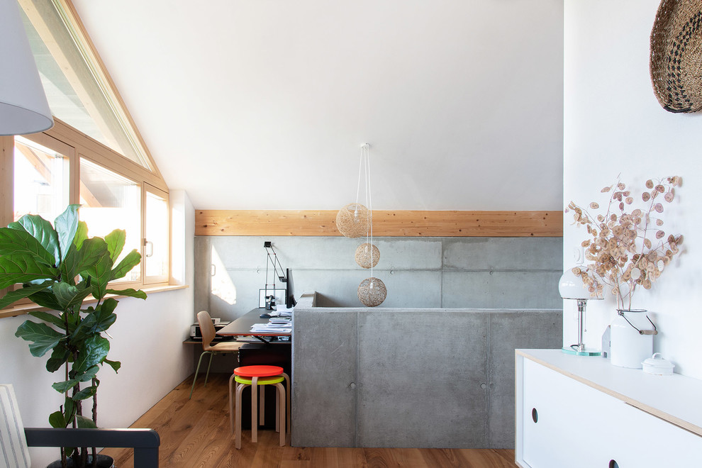 Foto di uno studio nordico con pareti bianche, pavimento in legno massello medio, scrivania autoportante e pavimento marrone