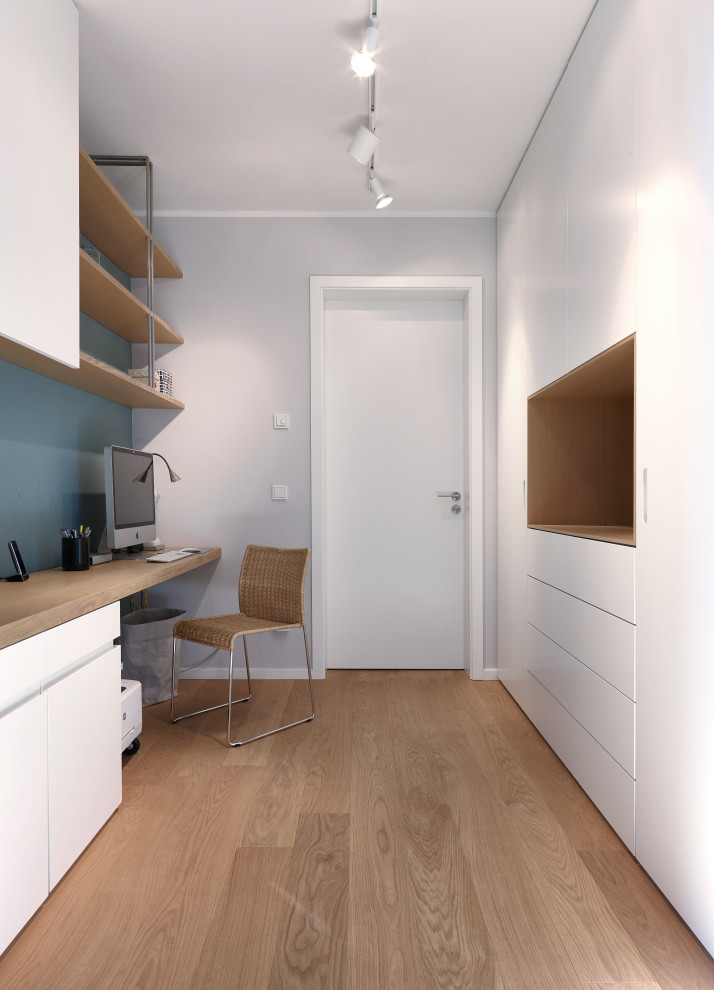 Inspiration pour un grand bureau design avec un mur bleu, un sol en bois brun, un bureau intégré et un sol marron.