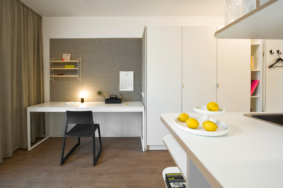 Ejemplo de despacho nórdico pequeño sin chimenea con paredes blancas, suelo de madera en tonos medios, escritorio independiente y suelo marrón