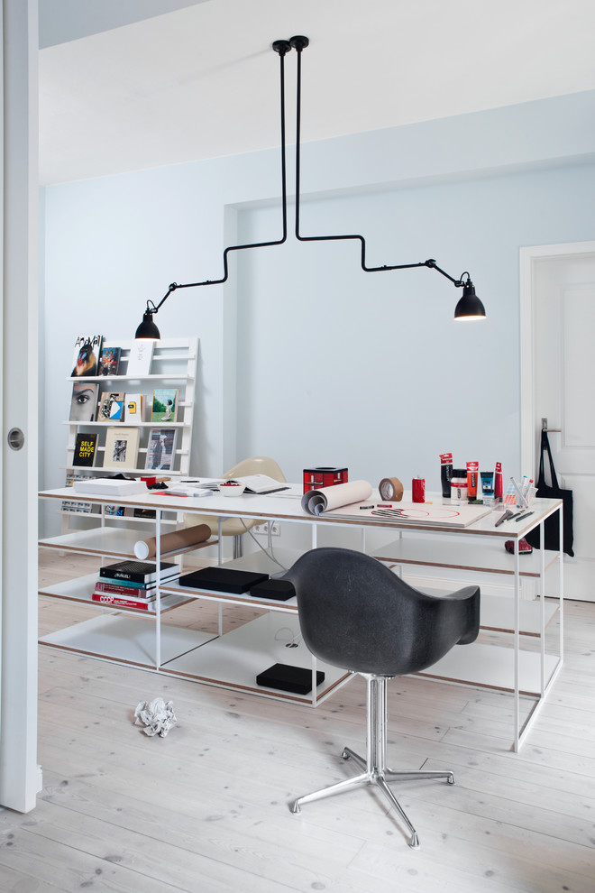 Diseño de despacho nórdico grande sin chimenea con paredes azules, suelo de madera clara y escritorio independiente