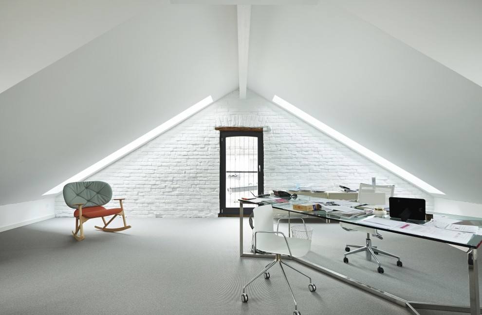 Пример оригинального дизайна: огромное рабочее место в стиле лофт с белыми стенами, ковровым покрытием и отдельно стоящим рабочим столом без камина
