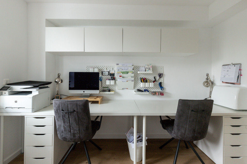 Ispirazione per un piccolo ufficio moderno con pareti bianche, parquet chiaro, scrivania incassata e pavimento beige