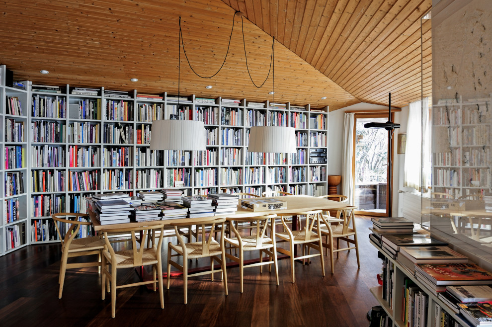 Aménagement d'un grand bureau montagne avec une bibliothèque ou un coin lecture, un mur blanc, un sol en bois brun, un bureau indépendant et un sol marron.