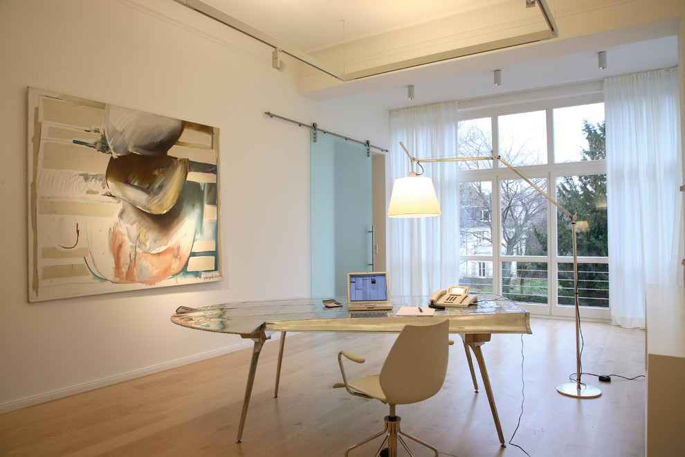 Modernes Arbeitszimmer mit Arbeitsplatz, weißer Wandfarbe, hellem Holzboden und freistehendem Schreibtisch in Köln