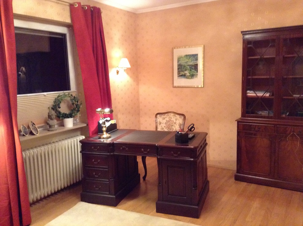 Kleines Landhausstil Arbeitszimmer mit Arbeitsplatz, hellem Holzboden, freistehendem Schreibtisch und gelber Wandfarbe in Köln