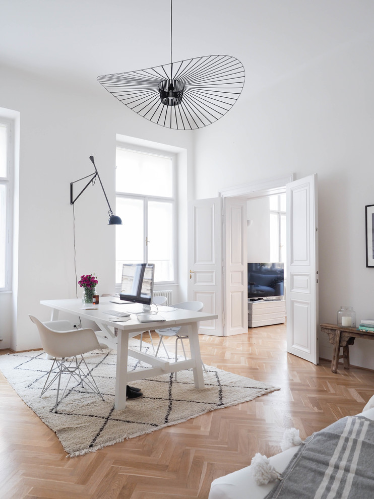 Mittelgroßes Skandinavisches Arbeitszimmer ohne Kamin mit freistehendem Schreibtisch, weißer Wandfarbe, braunem Holzboden, braunem Boden und Arbeitsplatz in Hannover