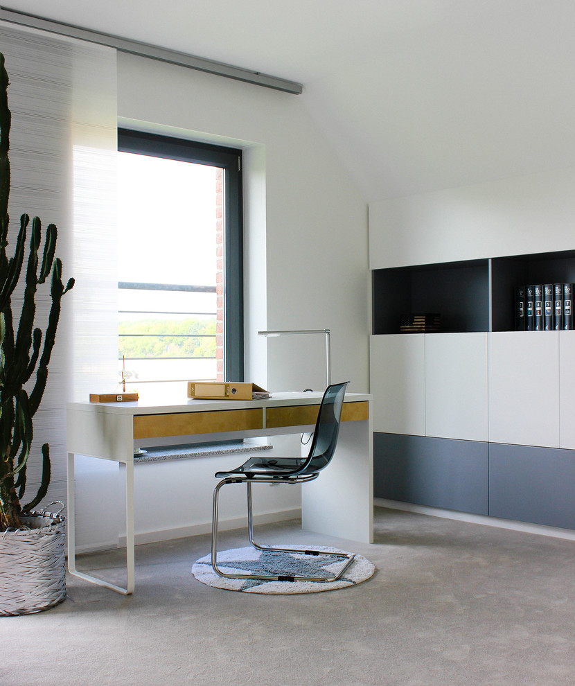 Mittelgroßes Modernes Arbeitszimmer ohne Kamin mit Arbeitsplatz, weißer Wandfarbe, Teppichboden und freistehendem Schreibtisch in Düsseldorf