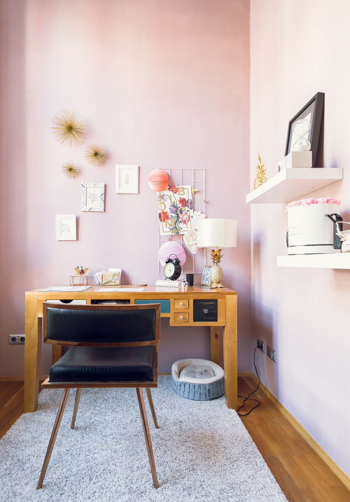 На фото: маленькое рабочее место в скандинавском стиле с розовыми стенами, паркетным полом среднего тона и отдельно стоящим рабочим столом для на участке и в саду