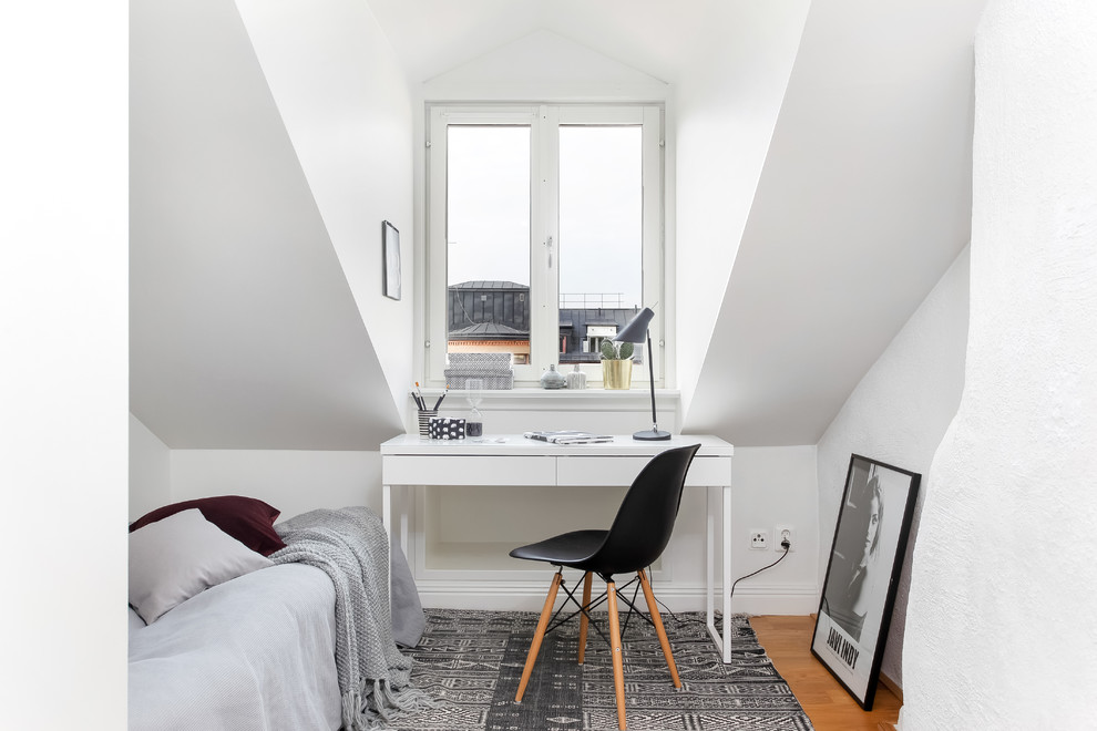 Bild på ett mellanstort skandinaviskt hemmastudio, med vita väggar, ljust trägolv och ett fristående skrivbord