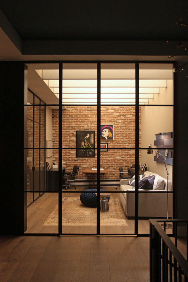 Modelo de estudio contemporáneo grande con paredes beige, suelo de madera en tonos medios y escritorio independiente