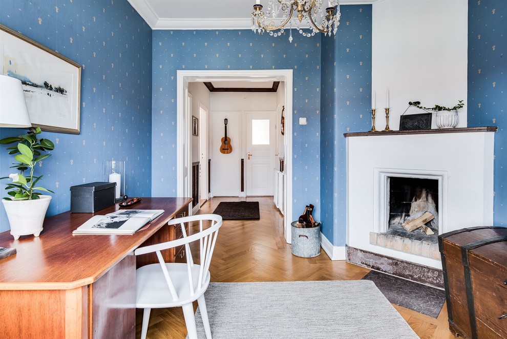 Landhaus Arbeitszimmer mit blauer Wandfarbe, braunem Holzboden und freistehendem Schreibtisch in Göteborg