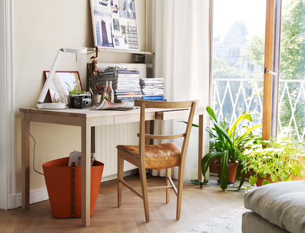 Skandinavisches Arbeitszimmer ohne Kamin mit Arbeitsplatz, beiger Wandfarbe, braunem Holzboden und freistehendem Schreibtisch in Malmö