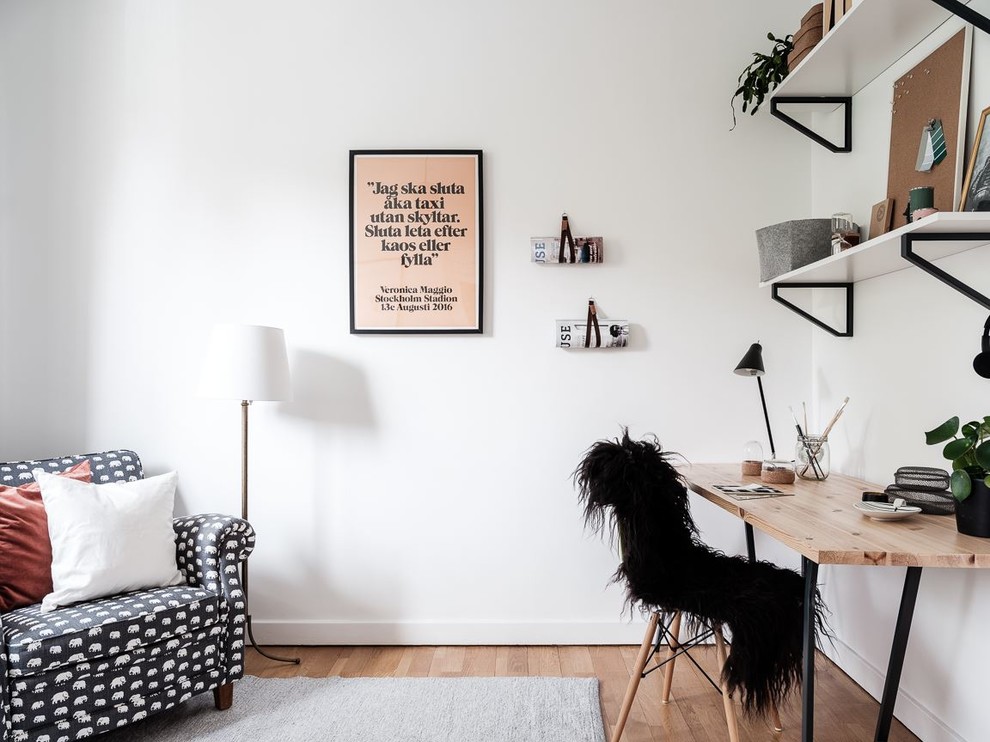 Idéer för ett nordiskt arbetsrum, med vita väggar, mellanmörkt trägolv, ett fristående skrivbord och brunt golv