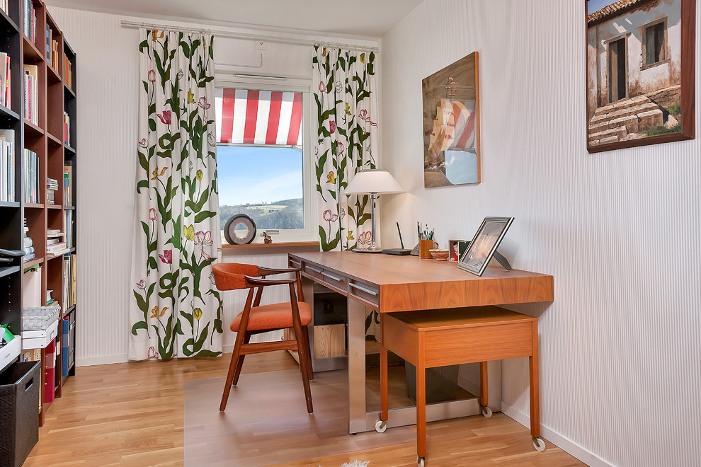 Mittelgroßes Nordisches Arbeitszimmer mit Arbeitsplatz, weißer Wandfarbe, braunem Holzboden und freistehendem Schreibtisch in Malmö