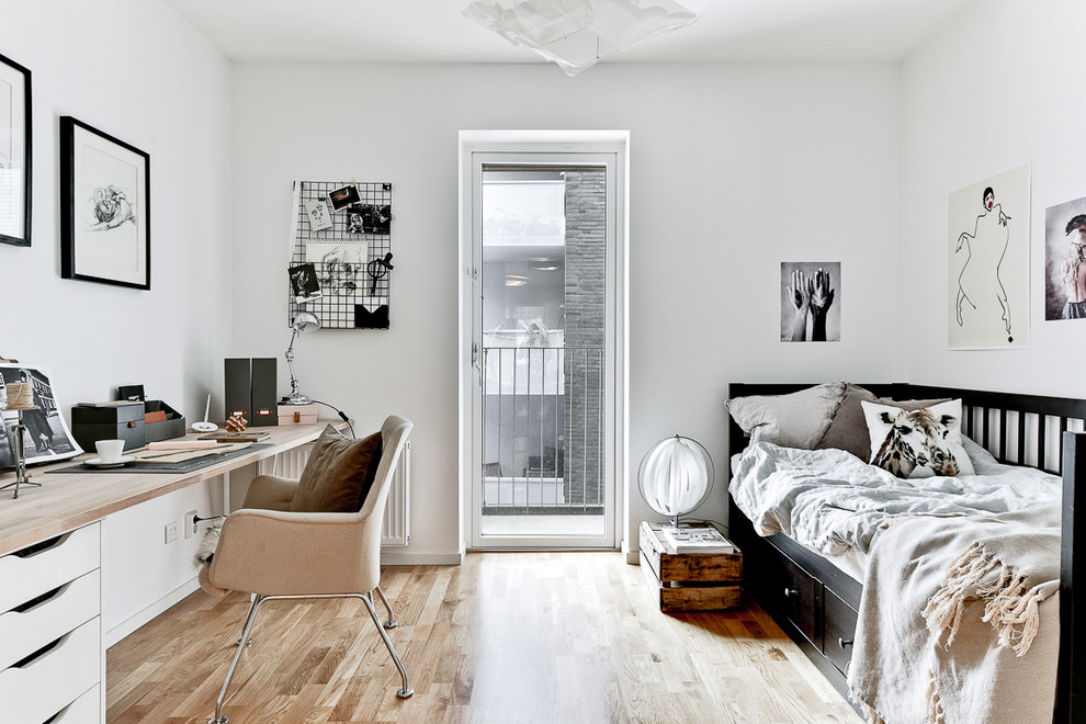 Mittelgroßes Skandinavisches Arbeitszimmer mit weißer Wandfarbe, braunem Holzboden und freistehendem Schreibtisch in Stockholm