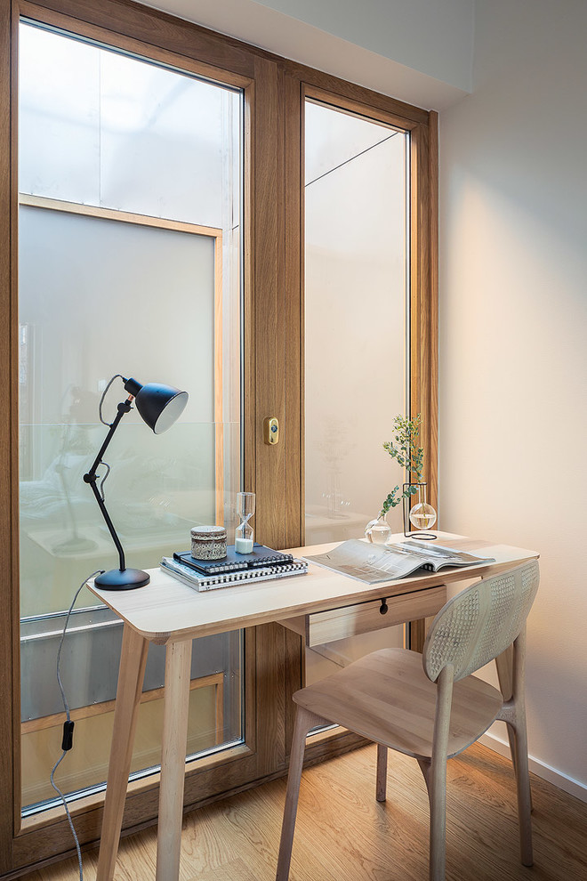 Mittelgroßes Modernes Arbeitszimmer ohne Kamin mit weißer Wandfarbe, hellem Holzboden, freistehendem Schreibtisch und Arbeitsplatz in Stockholm