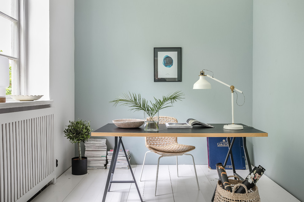 Kleines Nordisches Arbeitszimmer mit grüner Wandfarbe, gebeiztem Holzboden, freistehendem Schreibtisch und weißem Boden in Malmö