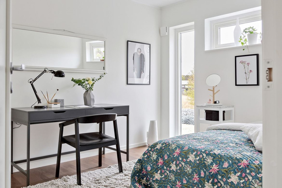 Idéer för att renovera ett mellanstort minimalistiskt arbetsrum, med vita väggar, mellanmörkt trägolv och ett fristående skrivbord