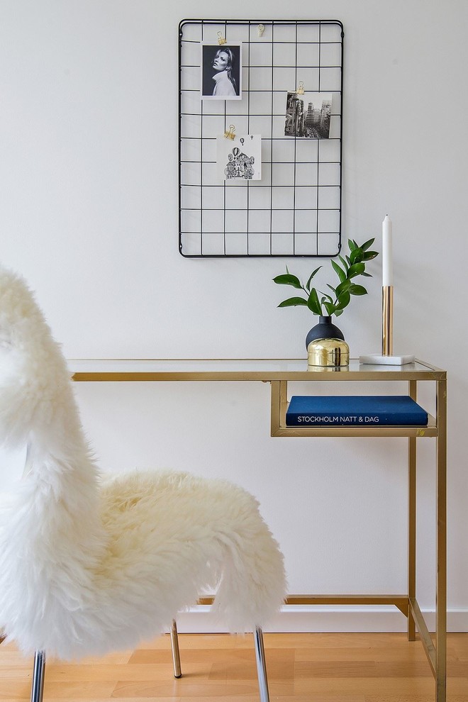 Ejemplo de despacho nórdico con paredes blancas, suelo de madera en tonos medios y escritorio independiente
