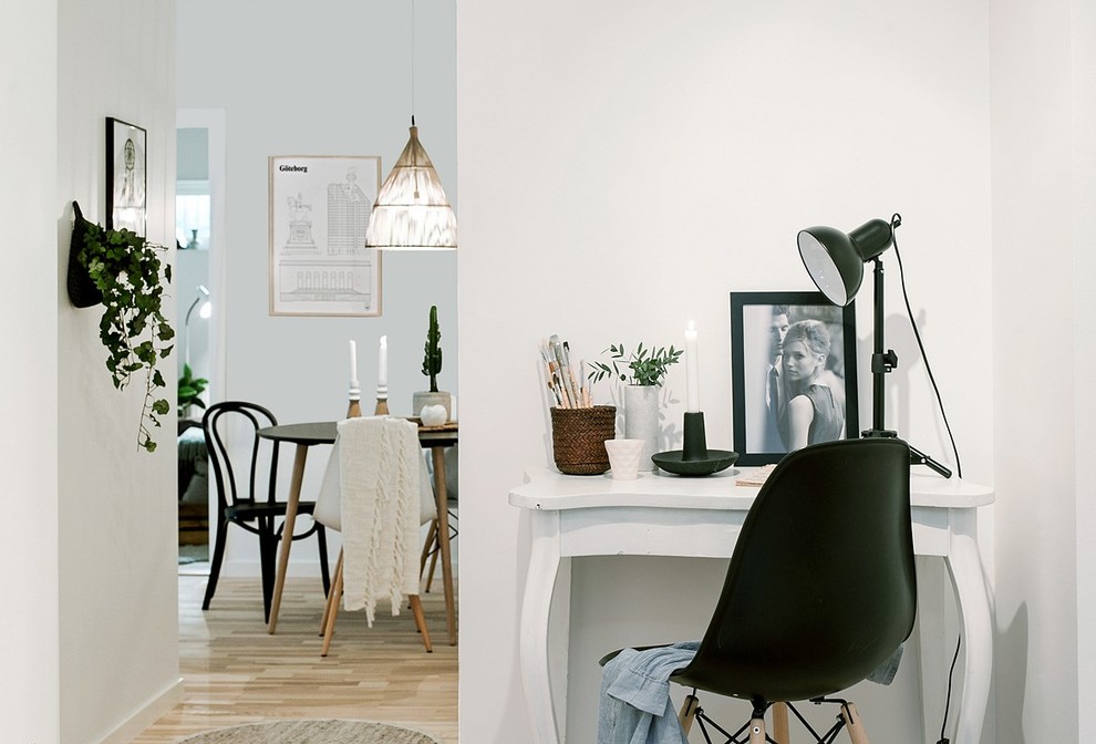 Foto på ett minimalistiskt hemmabibliotek, med vita väggar, ljust trägolv och ett fristående skrivbord