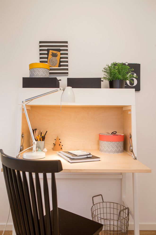 Exempel på ett litet minimalistiskt hemmabibliotek, med vita väggar, ett fristående skrivbord och mellanmörkt trägolv