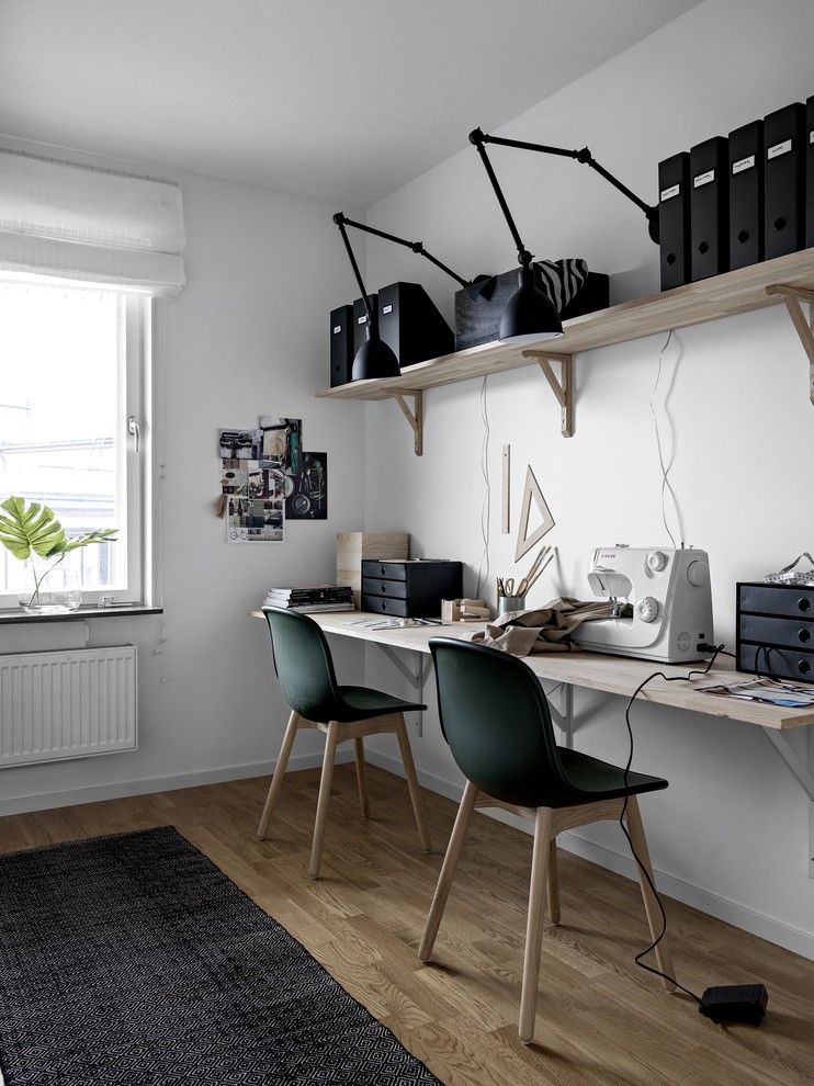 Immagine di un atelier minimalista di medie dimensioni con pareti bianche, pavimento in legno massello medio, scrivania incassata e pavimento marrone
