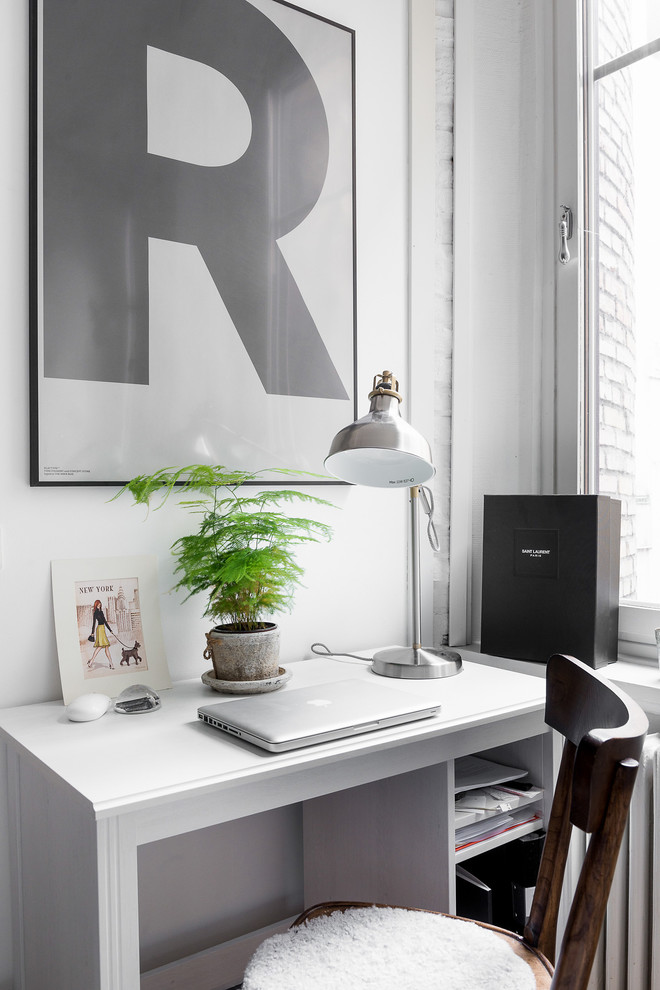 Foto på ett litet minimalistiskt arbetsrum, med vita väggar, mellanmörkt trägolv och ett fristående skrivbord