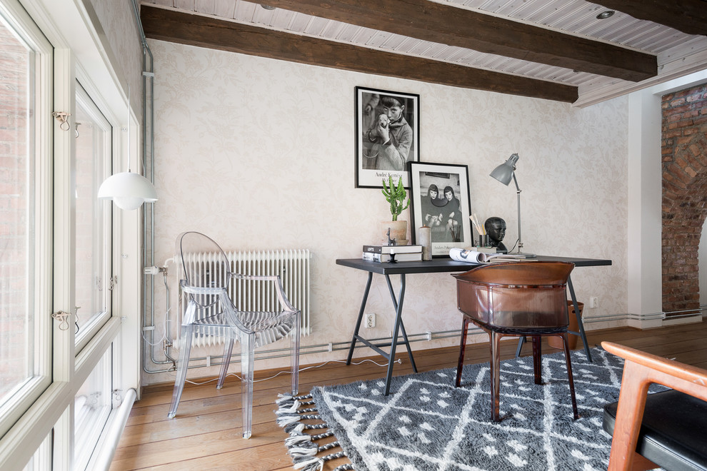 Minimalistisk inredning av ett litet arbetsrum, med beige väggar, mellanmörkt trägolv, ett fristående skrivbord och brunt golv