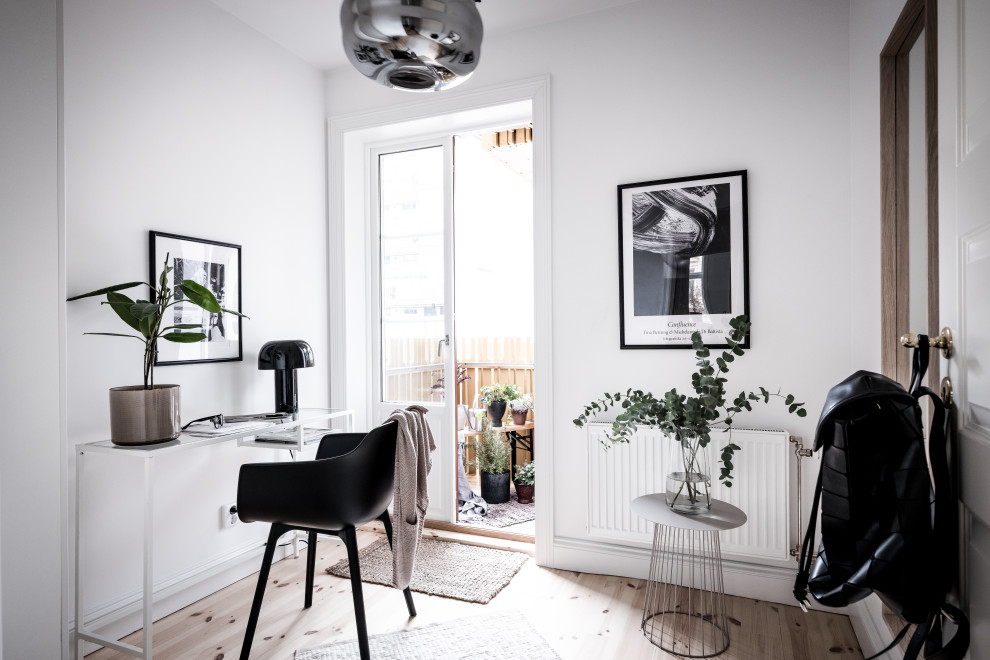 Immagine di uno studio scandinavo con pareti bianche, parquet chiaro, scrivania autoportante e pavimento beige