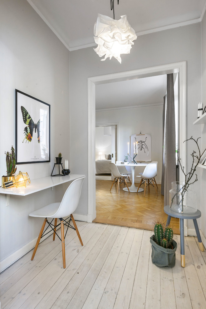Nordisk inredning av ett mellanstort arbetsrum, med grå väggar, ljust trägolv och ett inbyggt skrivbord