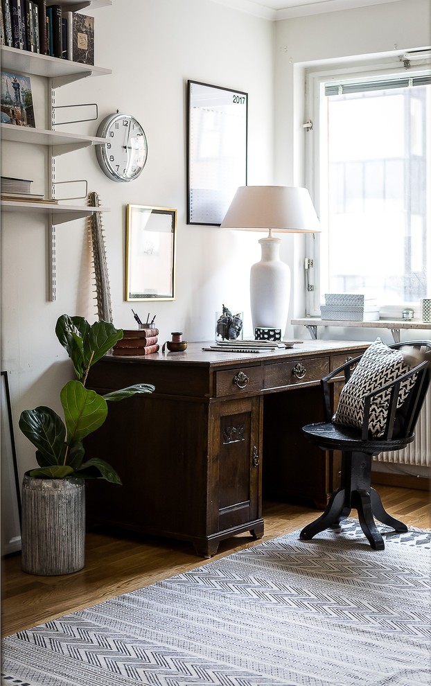 Diseño de despacho tradicional pequeño con paredes blancas, suelo de madera en tonos medios y escritorio independiente