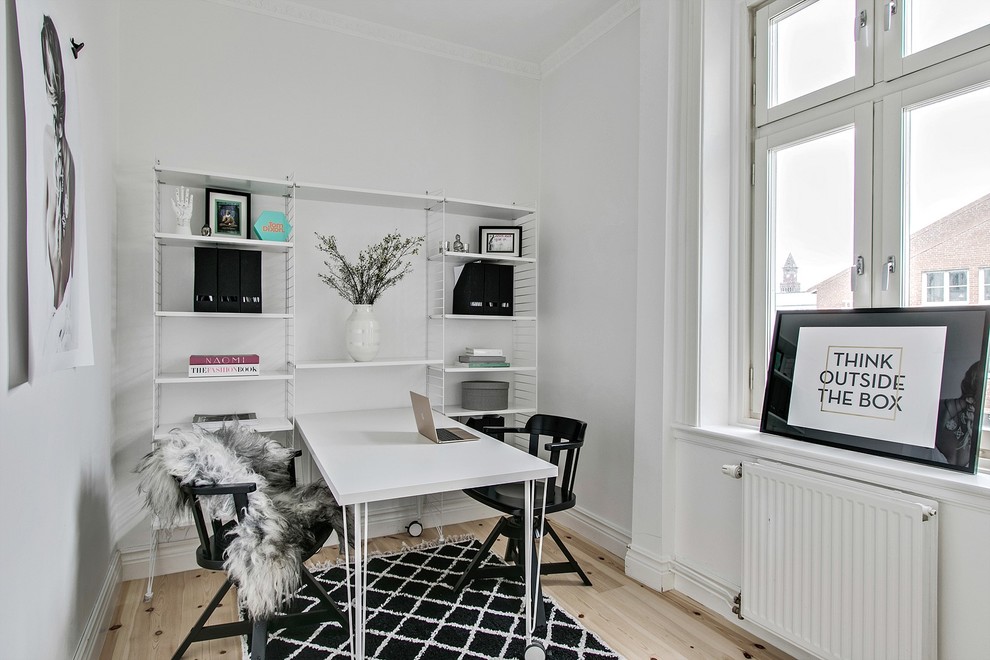 Exempel på ett mellanstort skandinaviskt hemmabibliotek, med vita väggar, ljust trägolv, ett fristående skrivbord och beiget golv