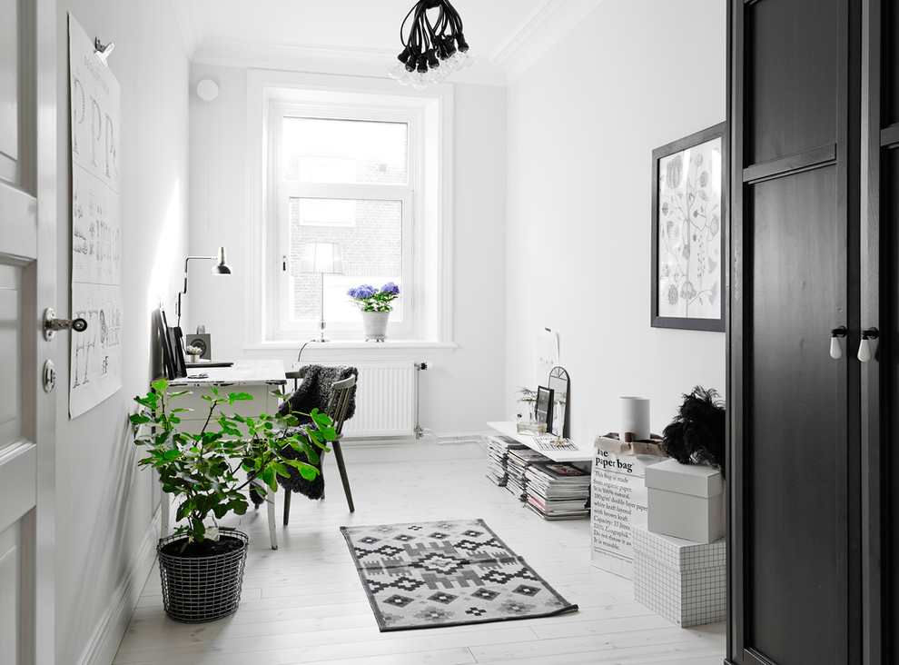 This is an example of a medium sized scandi study in Gothenburg with white walls, light hardwood flooring, no fireplace and a freestanding desk.