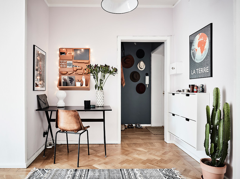 Источник вдохновения для домашнего уюта: рабочее место в скандинавском стиле с белыми стенами, паркетным полом среднего тона и отдельно стоящим рабочим столом без камина